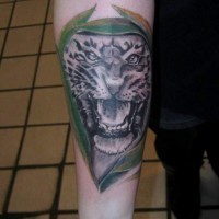 Tatuaje en el antebrazo, tigre gris entre hojas verdes