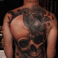 Tatuaje en la espalda,
cráneo grande volumétrico con bandada de cuervos