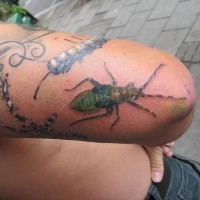 Green bug tattoo on thigh