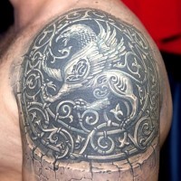 grifone di pietra con riccioli tatuaggio su spalla
