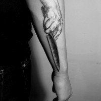 Hand with sharp knife detailed tattoo on forearm zone