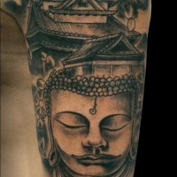 Homemade carelessly painted black ink Buddha statue tattoo on shoulder with antic house