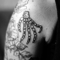Homemade cartoon style small funny skeleton hand tattoo on shoulder