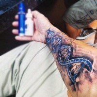 Hausgemachte große detaillierte blau gefärbte DNA Tattoo am Arm