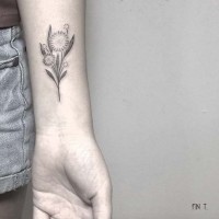 Homemade like black int tiny flower tattoo on forearm