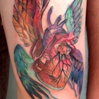 Homemade like watercolor style thigh tattoo of human heart with various wings