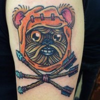 Homemade style colored smiling ewok face tattoo on shoulder with crossed arrows