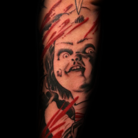 Horror movie doll tattoo on forearm with bloody stripes