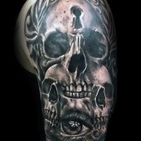 Horror style creepy looking upper arm tattoo of skulls with keyhole