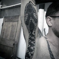 Huge detailed snake tattoo on man's arm and side in traditional old style