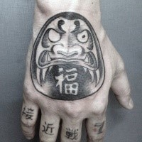 Illustrative style black and white hand tattoo of daruma doll with lettering