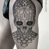 Illustrative style black ink thigh tattoo of alien skull stylized with ornaments