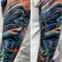 Illustrative style colored forearm tattoo of underwater sharks and fishes