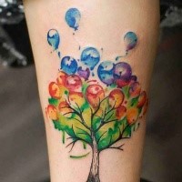 Illustrative style colored leg tattoo of tree with balloons