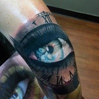 Illustrative style colored leg tattoo of woman eye with clock