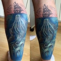 Illustrative style colored leg tattoo of small ship with large underwater monster