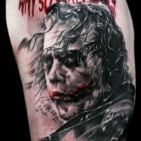 Illustrative style colored shoulder tattoo of Joker face and lettering