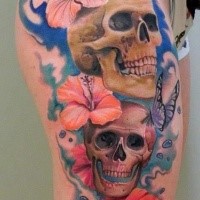Illustrative style colored thigh tattoo of human skulls with flowers and butterflies