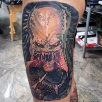 Illustrative style colored thigh tattoo of creepy Predator face