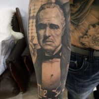 Impressive natural looking black ink God Father portrait tattoo on forearm with lettering