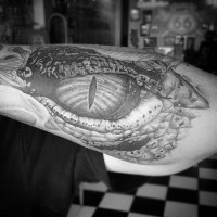 Beeindruckender sehr detaillierter schwarzer und weißer Alligator Auge Tattoo am Arm