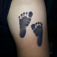 impronti di piedi bambino tatuaggio su spalla di uomo