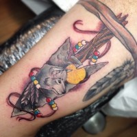 Tatuaje en el antebrazo, punta de flecha decorada con lobo y perlas