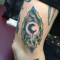 Tatuaje en el brazo, punta de flecha de piedra decorada con luna negra