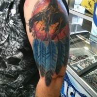 Tatuaje en el brazo, atrapasueños multicolor y hombre a caballo