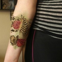 Tatuaje en el antebrazo, esqueleto humano realista con rosa y mariposa