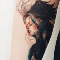 Tatuaje en el antebrazo, mujer linda con alas de cuervo