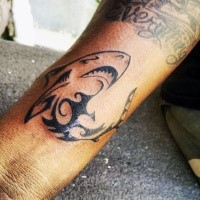 Interesting looking black ink Polynesian shark tattoo on arm