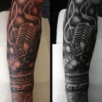 Interesting music themed black and white microphone with music tape tattoo on arm