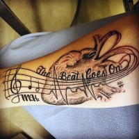 Interesting music themed black ink notes with lettering and heart tattoo on arm