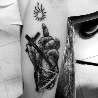 Tatuaje en el antebrazo, mano atada con cruz blanco negro