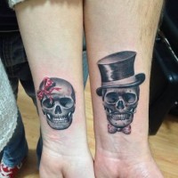 Tatuaggio carino sui bracci il teschio maschile e il teschio femminile