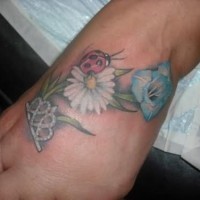 Tatuaje en la mano,  mariquita y dos flores