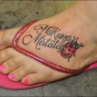Tatuaggio colorato sul piede la coccinella & la scritta