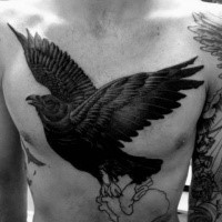 Large black ink chest tattoo of flying crow with human heart