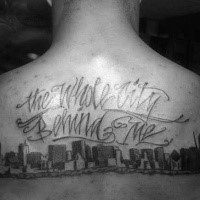 Large black ink upper back tattoo of city sights and lettering