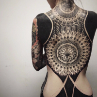 Large blackwork style whole back tattoo combined with ornamental flowers