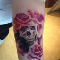 Tatuaje en el antebrazo, cráneo humano pequeño entre flores