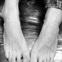 Little beautiful looking white ink flowers tattoo on feet