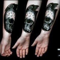 Little black and white clock with skull tattoo on arm