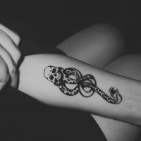 Little black ink old school snake tattoo on forearm stylized with skull