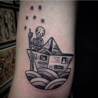 Tatuaje en el brazo, barco pequeño de papel con esqueleto