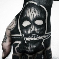 Little cartoon like black ink monster mask with knife tattoo on hand