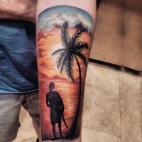 Tatuaje en el antebrazo, surfista en la playa a puesta del sol