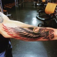 Little multicolored lion with wing tattoo on arm