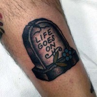 Little simple painted tombstone with flowers tattoo on leg